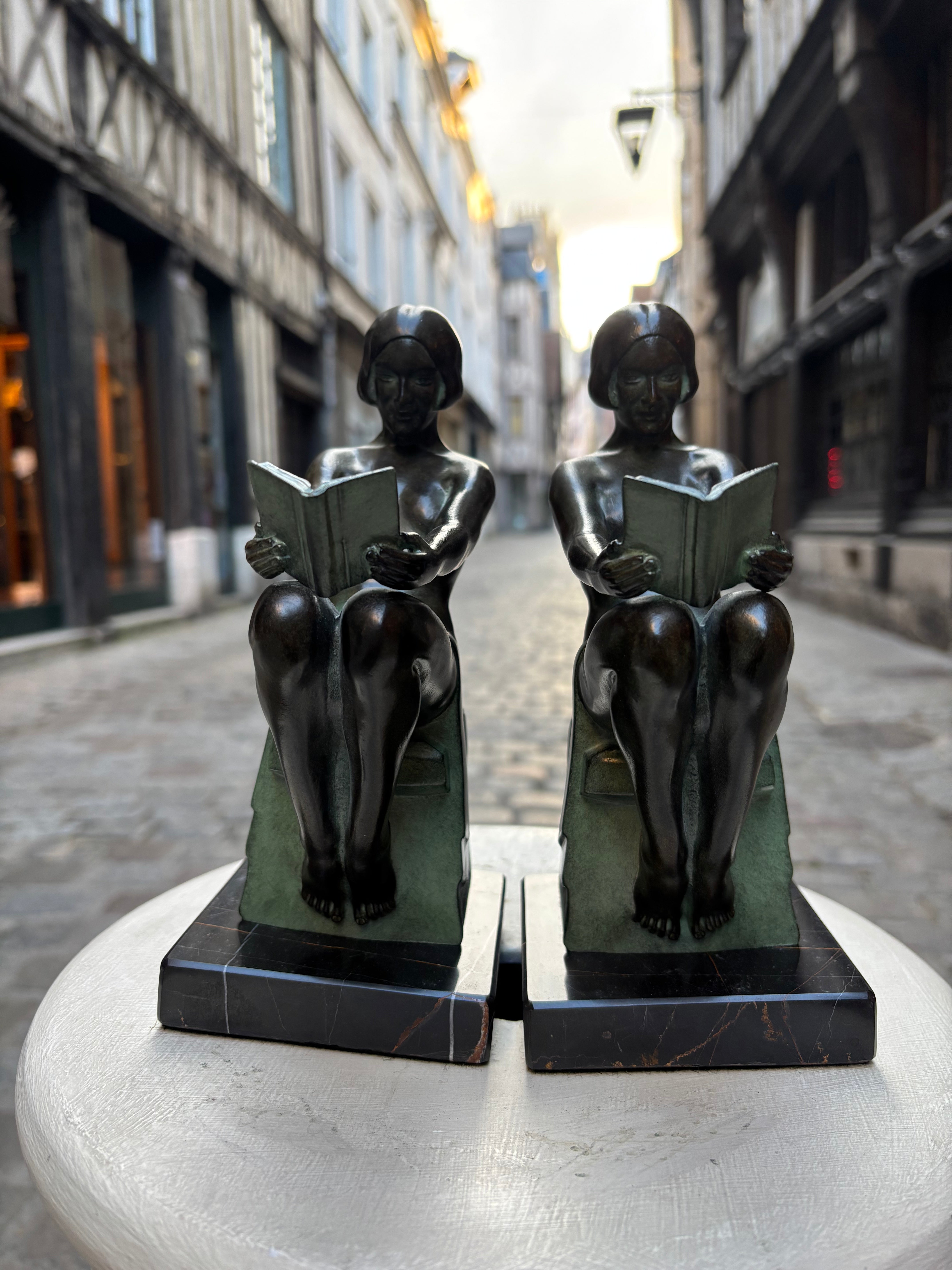 Paire de serre livres "Délassement";Max LE VERRIER, de style Art Déco avec cachet de fondeur Le Verrier.
Élégante composition représentant une femme à la lecture, conçue vers 1928 et réalisée en métal d'art patiné sur socle en marbre.